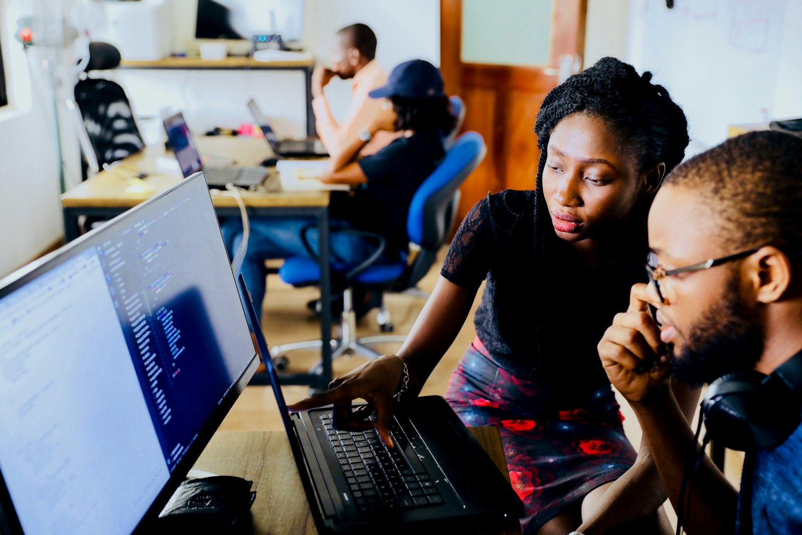 Two engineers reviewing code together at a desk in an open office